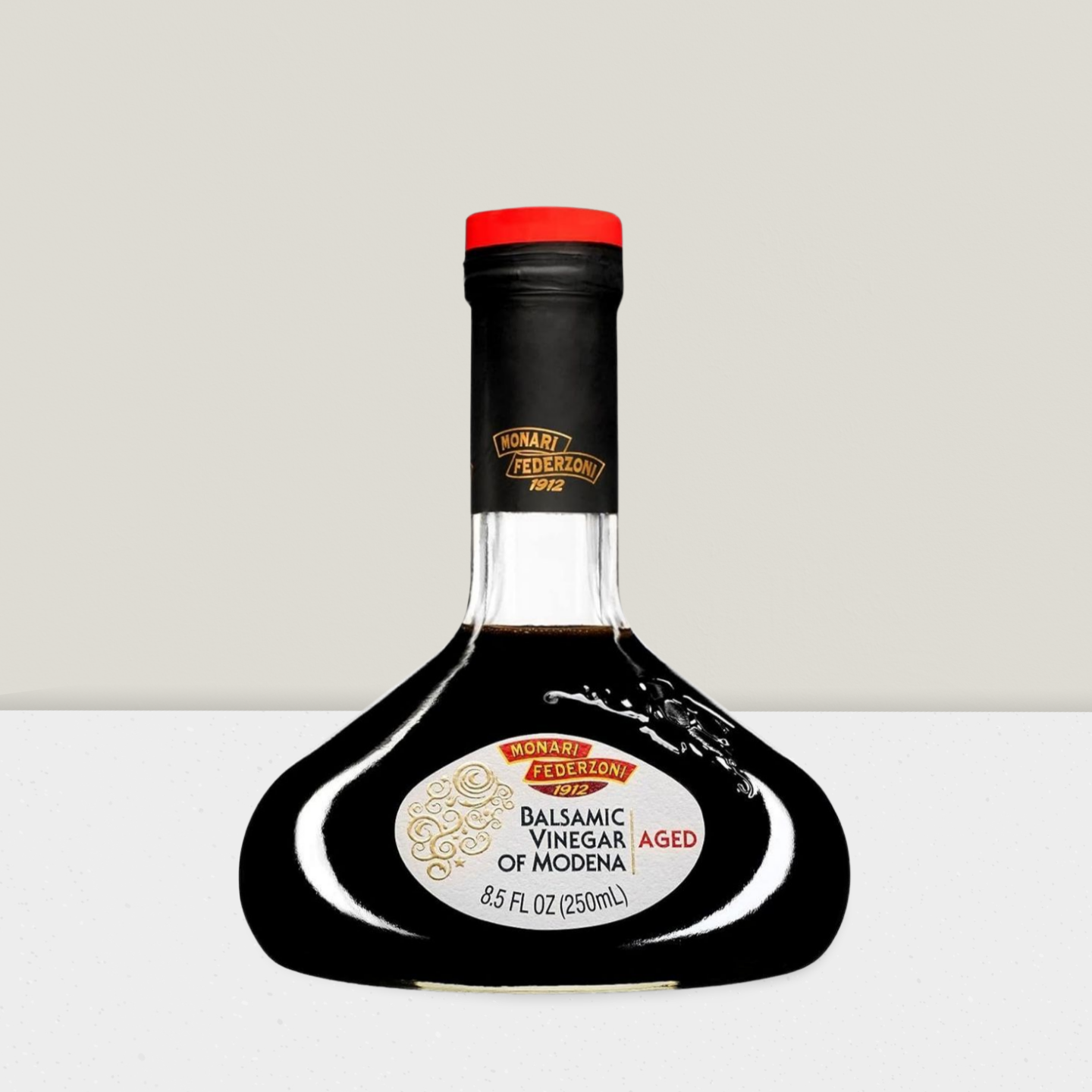 Bottle of Balsamic Vinegar of Modena with a black label on a light gray background